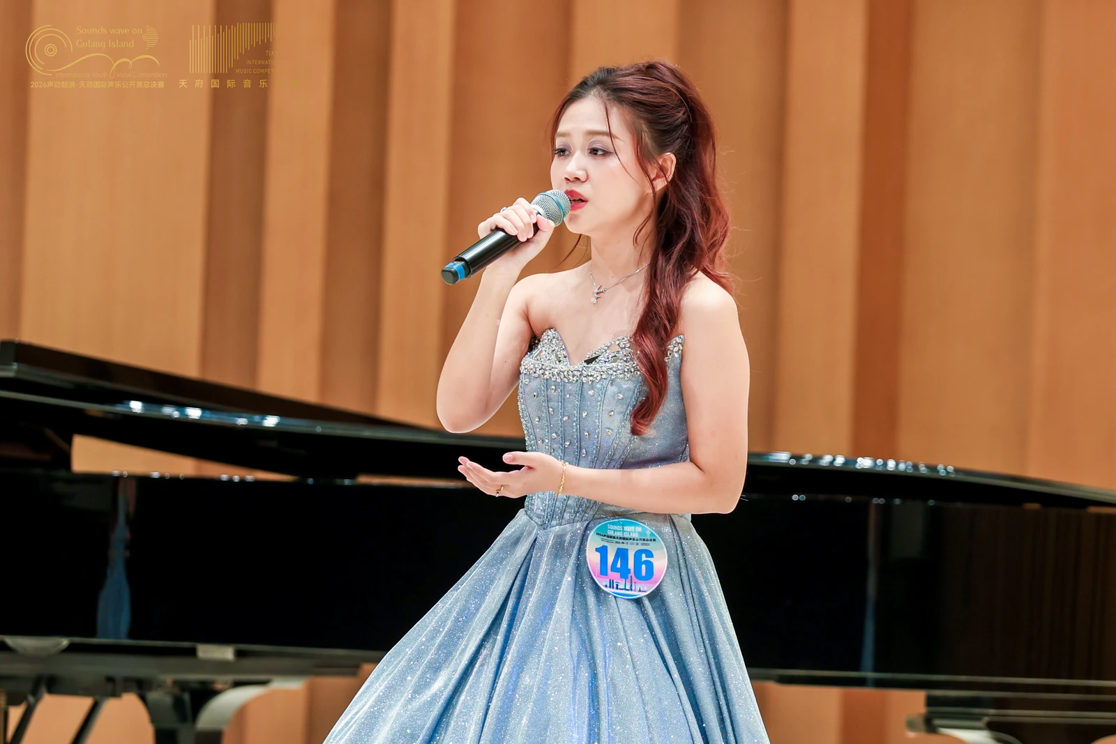 Eugenie performing in a pale blue gown beside a grand piano