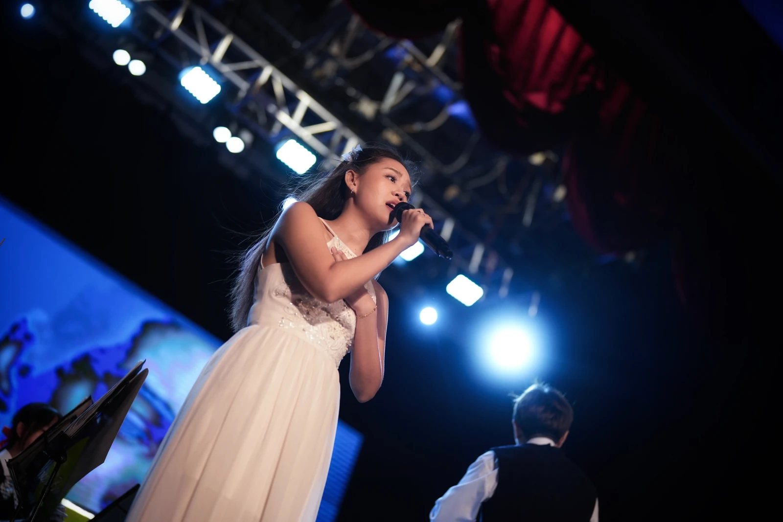 Eugenie performing in a white gown beneath blue stage lights